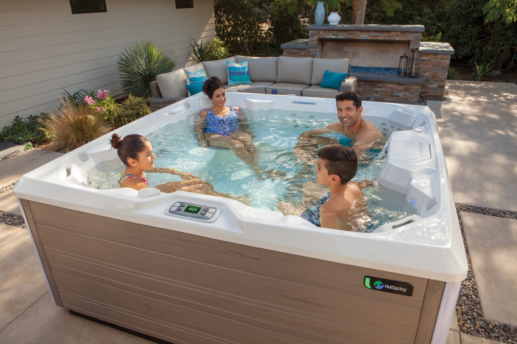 A family using a HotSpring Limelight Pulse hot tub in a garden